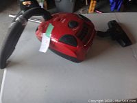 Photo of red Bissell Zing canister vacuum cleaner showing hose, wand, and floor nozzle on a table.
