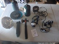 Full view of all items including two propane tanks, single burner cooktop, air pump, headband light, tent pegs, and multi-tool with hammer and axe.