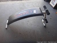 Side angle view of black padded Champs Sports sit up and leg curl bench, showing foam rollers and metal frame.