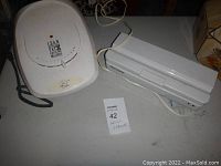 Both the George Foreman grill and FoodSaver bag sealer shown from a front angle on a table with power cords visible.