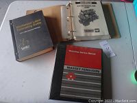Overview photo of three manuals on table: Mechanical Labor Estimating Guide by ShopKey, Caterpillar Heavy Duty Mechanical Engines binder, and Massey Ferguson Workshop Service Manual.