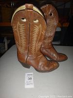 Pair of tan leather cowboy boots standing upright showing shaft stitching, pull holes, and overall shape.