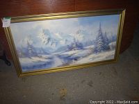 Frontal photo of the large vintage painting showcasing the snowy mountain landscape and gold frame.