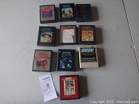 Photo showing all 10 Atari 2600 video game cartridges arranged on a flat surface, including one with a boxing label and one with a white case labeled Smurf.