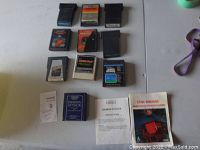 Lot of 10 Atari 2600 cartridges laid out with some original instruction booklets visible for Demon Attack and Cosmic Ark.