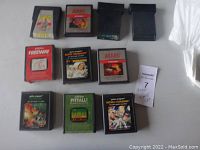 Top view of all 10 Atari 2600 video game cartridges arranged on a surface, showing original labels and varying colors of cartridge cases.