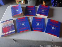 Overview of eight used Chrysler car repair manuals and parts books arranged on a table, showing wear and varied thickness.