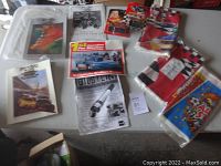 Overview of the lot showing race programs, diecast cars in packaging, and folded NASCAR-themed table coverings.