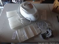 Full view of the Revlon paraffin wax warmer with wax blocks, metal insert, gloves, power cord, and instruction manual on a table.