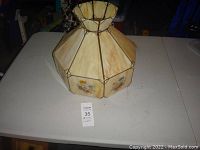 Tiffany style mult-panel light shade shown from top down angle on white table. Shows ruffled top and octagonal shape.