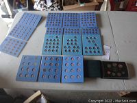 Overall photo of the US and Canadian coin collection in blue coin folder books and black collector case on a white table.