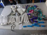 Wide view of all items displayed on table showing pillars, cookie cutters, piping bags, blue Wilton labels, white cake spinner, and assorted tools.