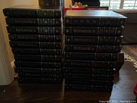 Full set of leather bound Encyclopedia Britannica volumes stacked in two piles, showing volumes from 13 to 29.