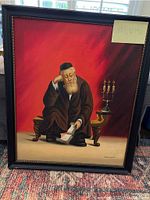 Frontal photo of the larger oil painting depicting a seated elderly rabbi holding a book next to a menorah, signed Kaminski, 23 x 19 inches