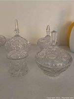 Four European crystal candy dishes with matching lids showing the various detailed cut designs and different faceted finial shapes on each lid