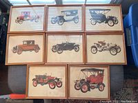 Overhead photo showing all eight framed automotive prints laid flat on the floor, highlighting the uniform size and framing style of each print.