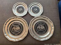 Four metal plates awarded by the Atlanta Lawn Tennis Association as city champion trophies, placed on a flat surface.