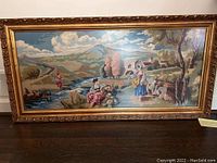 Full view of large framed crochet knit painting showing entire pastoral scene with sky, hills, trees, figures, and animals.