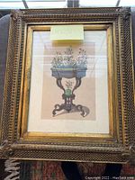 Front view of the framed print showing floral arrangement on an ornate table with gold decorative frame.