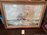 Front view of the large nautical ship print showing two sailing ships on the sea with detailed waves and clouds, framed in a gold-accented wooden frame.