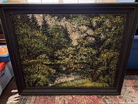 Frontal view of the framed textured painting showing dense trees, primarily green and brown.