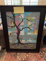 Front view of the framed abstract painting of a tree with multicolor geometric background, signed by Kelly.