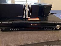 Front view of Panasonic SA-PT950 DVD player with attached speakers and cords visible
