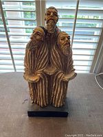 Front view of the sculpture featuring three rabbis with detailed robes and facial expressions.