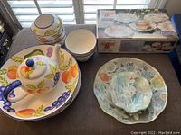 Overview of three sets: ceramic tea set with fruit design, boxed glass serving set, and white-blue bowls
