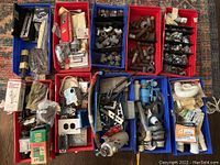 View of multiple plastic bins filled with plumbing fittings like elbow joints, couplings, valves, nuts, bolts, and gaskets.