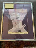Full view of the framed Vogue print showing the stylized Art Deco woman and bird illustration within the metal frame and matte.