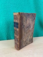 Front angled view of antique Shakespeare book showing leather spine and marbled cover.