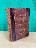 Front view of antique book with marbled pattern and leather spine and corners