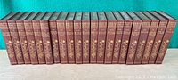 Photo showing full 25-volume set of "The Works of Rudyard Kipling" with maroon covers and gold detailing on spines.