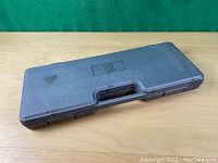 Closed grey plastic carrying case embossed with Powerfist logo on top, showing handle for portability.