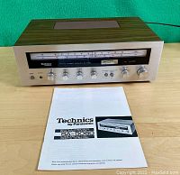 Receiver front panel and top view showing wood-grain case and manual positioned in front