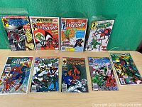 Front view of the lot showing eight colorful Amazing Spider-Man comic books arranged in two rows on a flat surface.