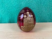 Front view showing the egg with an etched gold design of a building with onion dome architecture.