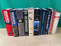 Full view of eleven hardcover novels showing titles and authors' names on spines.