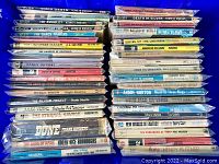 Photo showing stacks of vintage sci-fi paperback books wrapped in plastic sleeves, titles visible on spines.