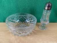 Waterford England signed crystal bowl next to a crystal sugar shaker with EPNS top, both placed on a wooden surface with a green background.