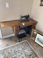 Front view of oak treadle table with Singer sewing machine head and storage drawers