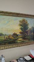 Full view of framed original oil painting showing landscape with tree, farmhouse, figures, and haystacks in carved gold-tone frame.