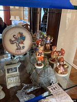 Shelf display with plate 1973 M.J. Hummel annual plate and five Goebel porcelain figurines.