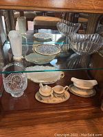 Display cabinet showing Lenox Autumn creamer and sugar set, serving bowl, two crystal bowls and decorative plate on top shelf.