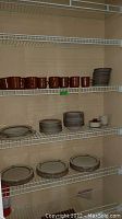 Shelves with brown cups and assorted plates and bowls in Macy's The Cellar dinnerware set