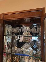 Glass cabinet displaying Mikasa black plates and various Waterford crystal stemware.