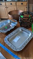 Overview of all items in the lot on table, including copper hammered bowl, metal wine basket, and two pewter serving platters