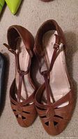 Top down view of the brown T-strap wedged heel shoes showing toe stitching and upper strap design.