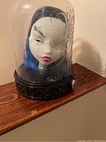 White Monster High doll head with blue and black hair inside a clear dome on black base, missing one eye